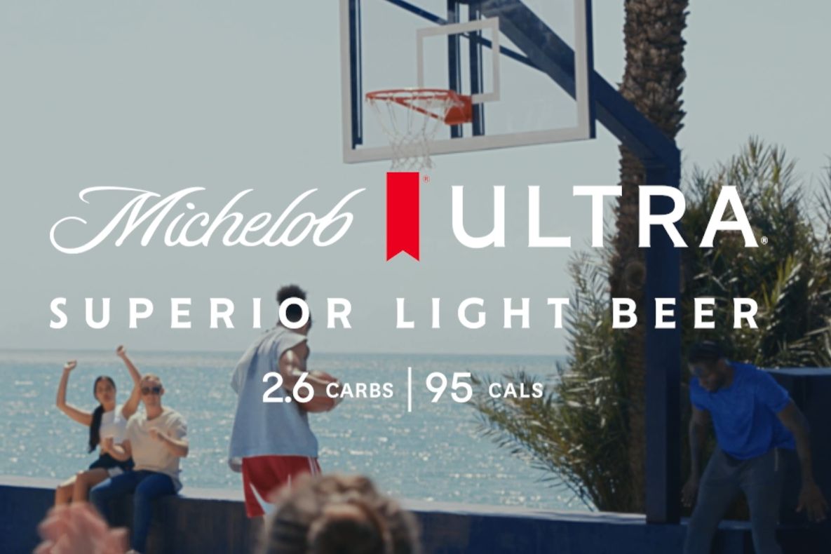 Michelob Ultra Superior Access Courtside ’25–’26 Sweepstakes promo image with a beachside outdoor basketball hoop and players on a court, featuring the Michelob Ultra logo and “Superior Light Beer” text. Basketball courtside sweepstakes creative showing an NBA-style scene near the ocean, highlighting Michelob Ultra branding and the Courtside ’25–’26 promotion. Promotional graphic for the Michelob Ultra Courtside sweepstakes featuring a basketball court setting and brand overlay.