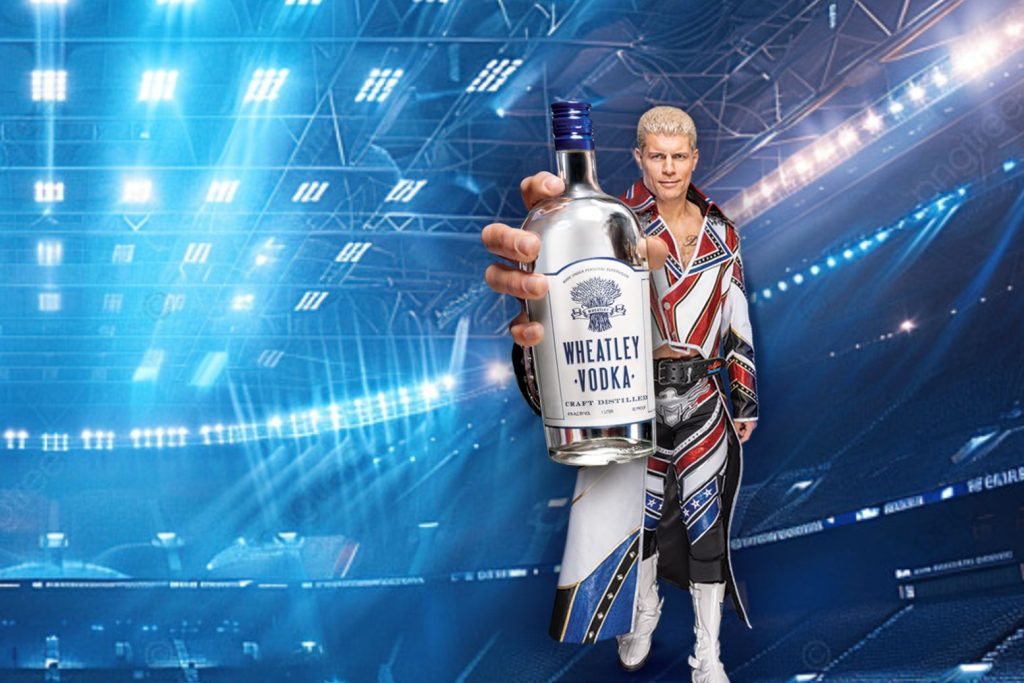 A pro wrestler holds a large Wheatley Vodka bottle toward the camera inside a bright arena, promoting the Wheatley Vodka Professional Wrestling Sweepstakes to win a WrestleMania 42 trip for two or regional WWE event tickets, a wrestling fan giveaway featuring the WrestleMania trip grand prize and WWE tickets as prizes.