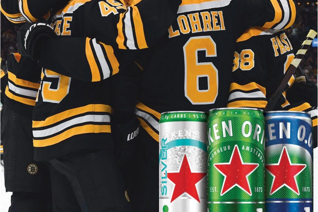 Boston Bruins players huddle in black and gold jerseys while three Heineken cans sit in the foreground, highlighting the Heineken Boston Bruins fan promotion and instant win giveaway prizes. A close-up sports celebration image featuring Bruins uniforms and Heineken Silver and other Heineken cans, used to represent a Bruins fan sweepstakes and Heineken giveaway. Hockey team celebration photo with Heineken branding in front, ideal for a Boston Bruins sweepstakes, instant win contest, and team shop gift card prize promotion.