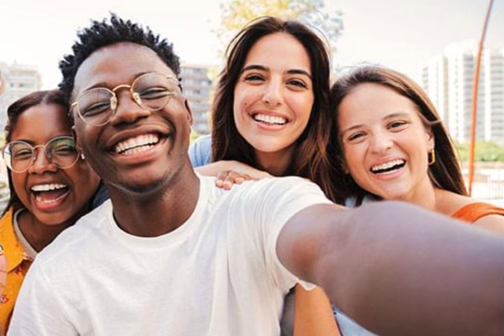 Group of smiling students taking a selfie outdoors, showing happy college-age friends together. Friendly scholarship sweepstakes image representing a Discover $5,000 scholarship giveaway for eligible students and families.
