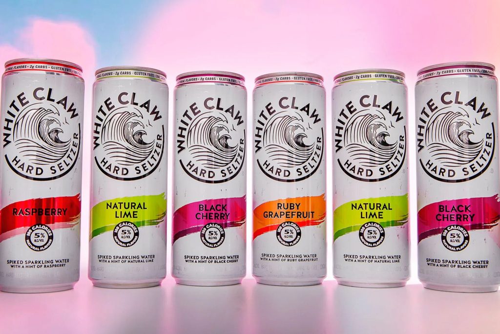 Six White Claw Hard Seltzer cans lined up in different flavors, representing the White Claw Home Theatre Sweepstakes prize promotion. White Claw hard seltzer cans shown in raspberry, lime, black cherry, and grapefruit flavors used to promote a $1,500 home theatre sweepstakes giveaway.