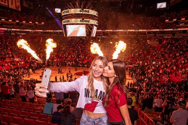 Miami Heat basketball game crowd with arena flames and fans taking selfie courtside for the Frito-Lay Miami HEAT Game Experience Sweepstakes