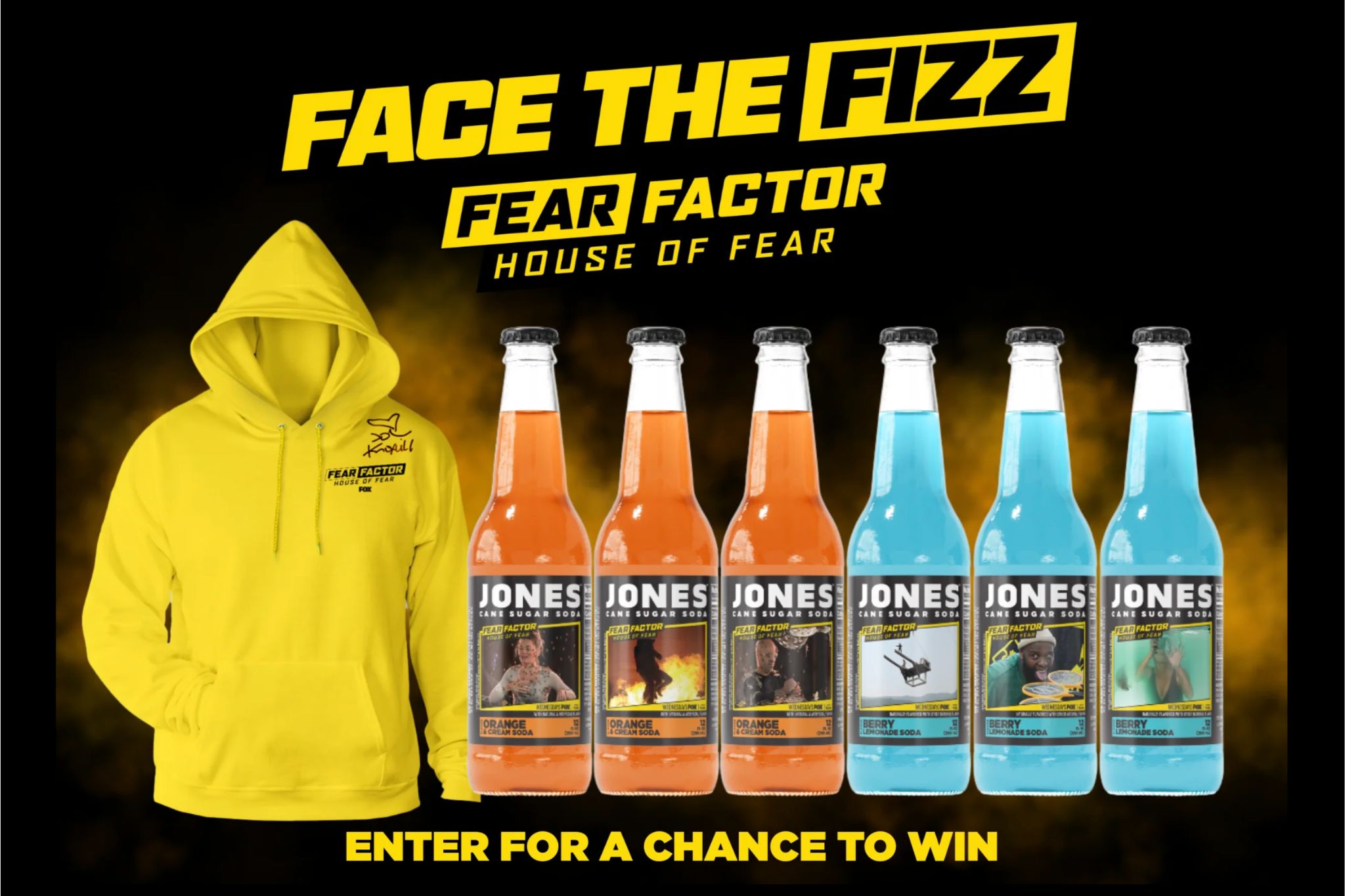 Promotional image for the Jones Soda Face the Fizz Contest featuring a bright yellow Fear Factor hoodie, six bottles of Jones Soda in orange and blue flavors, and bold text inviting viewers to enter for a chance to win a signed Johnny Knoxville pullover and year supply of Jones Soda. The graphic highlights the Face the Fizz Contest prize bundle and Fear Factor x Jones Soda collaboration with vibrant product shots and national bottle feature promotion.