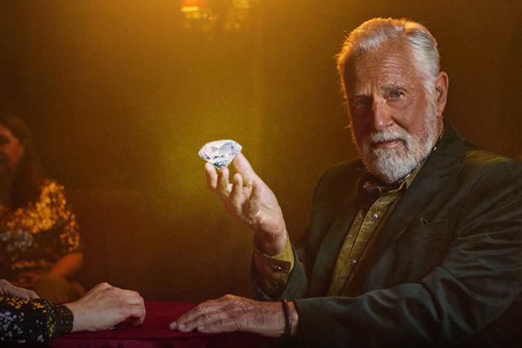 Image of the Dos Equis Most Interesting Man holding a large diamond, used to promote the Dos Equis Most Interesting Man Promotion with instant win and sweepstakes prizes. The photo highlights the Most Interesting Man theme and the chance to win Dos Equis merchandise kits like a bobblehead, bandana, socks, and playing cards through the 2026 promotion.