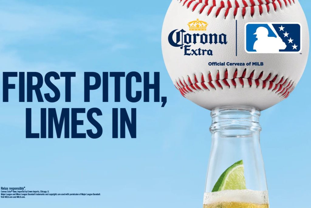 A baseball rests atop a beer bottle filled with a lime wedge, set against a blue sky, highlighting a playful blend of baseball and refreshing summer drinks, featured in the Corona MiLB Sweepstakes