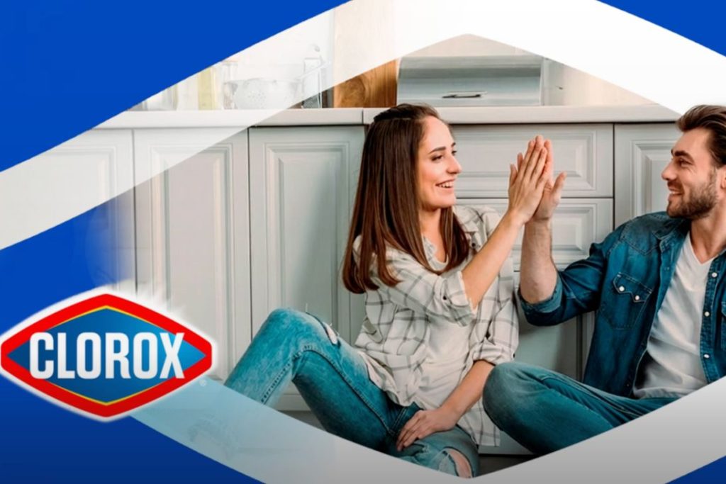 A woman and man are sitting on the floor in a bright kitchen, smiling and high-fiving each other, creating a joyful and playful atmosphere, featured in the Clorox Fresh Start Prize Pack Sweepstakes