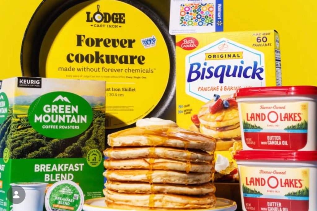 A stack of golden pancakes drizzled with syrup sits prominently against a bright yellow background, accompanied by coffee, pancake mix, and butter products, featured in the Bisquick Breakfast Giveaway Sweepstakes