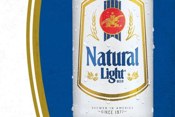 A chilled can of beer is prominently displayed, featuring a classic design with droplets of condensation on its surface, set against a vibrant blue background, featured in the Natural Light Gear Sweepstakes
