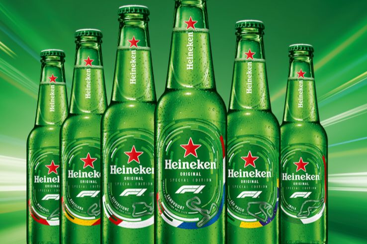 A vibrant display of Heineken beer bottles, featuring a variety of designs, stands against a dynamic green background, showcasing a refreshing selection for fans, featured in the Heineken Formula 1 Sweepstakes