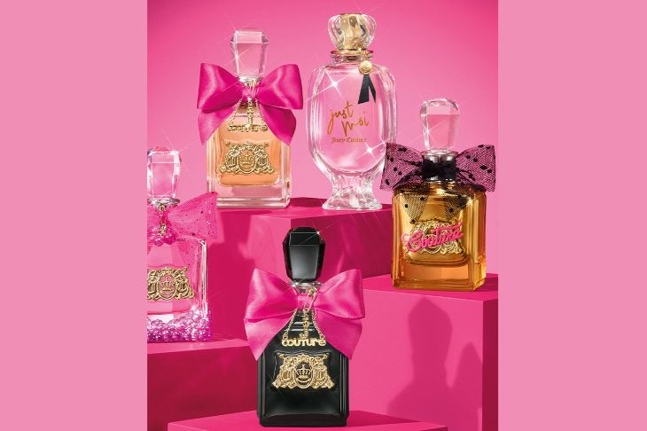 A vibrant display of five perfume bottles, adorned with pink bows and unique designs, set against a bright pink background, showcasing their elegant shapes and colors, featured in the Revlon Viva La Juicy Elixir Sweepstakes