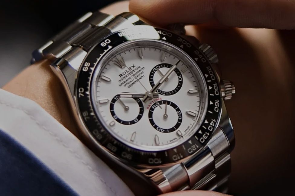 A close-up of a silver chronograph watch with a white dial, featuring black sub-dials. A hand adjusts the watch on the wrist, showcasing an elegant and sophisticated timepiece, featured in the Bobs Watches $5,000 Store Credit Sweepstakes