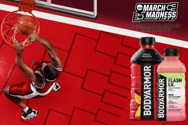 A basketball player leaps for a dunk on a vibrant red court, with two beverages displayed prominently beside him, capturing the energy of March Madness, featured in the BODYARMOR Final Four Trip Sweepstakes