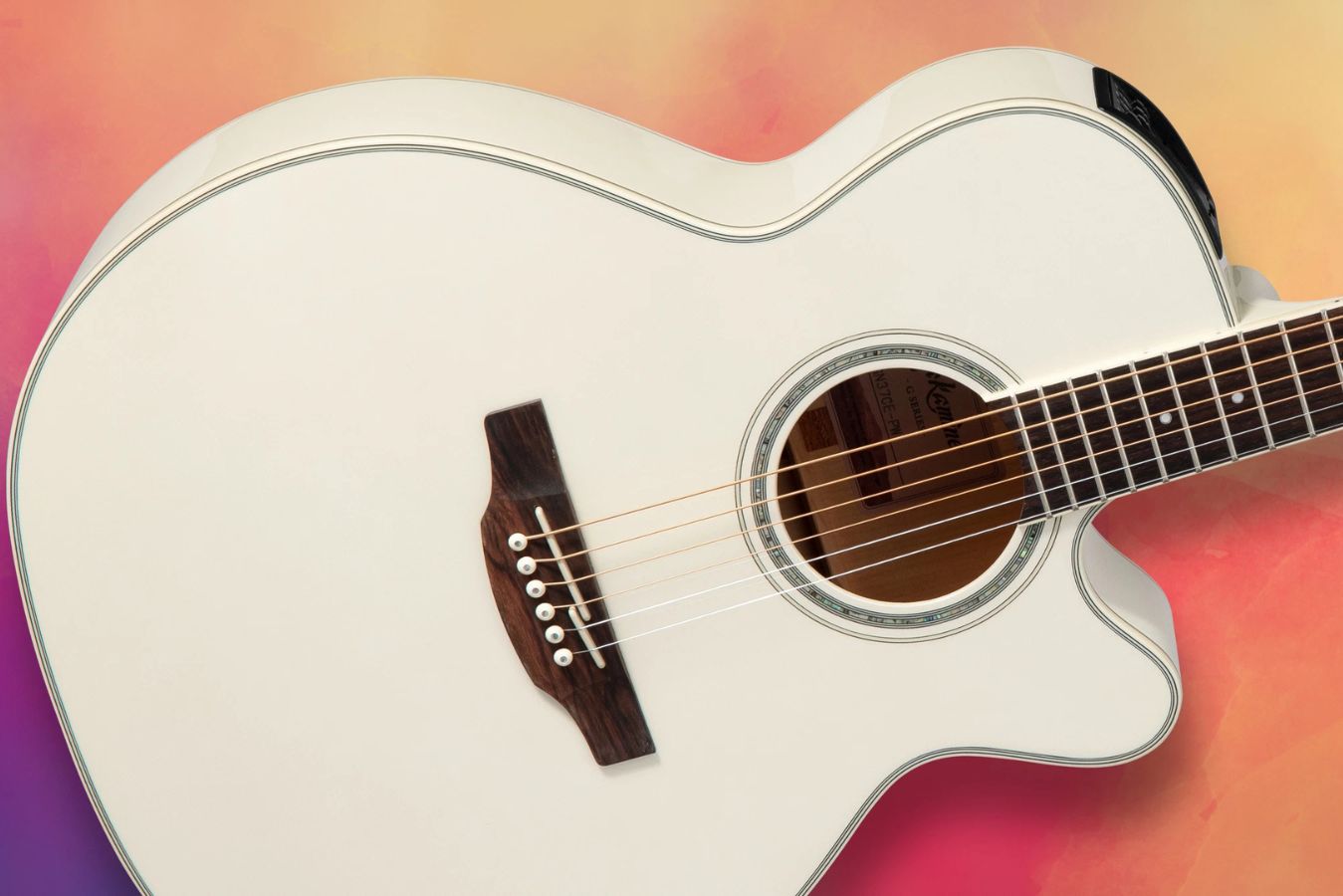 A close-up of a white acoustic guitar showcases its smooth curves and detailed fretboard, set against a vibrant pink and orange gradient background, featured in the Takamine GN37CE Sweepstakes