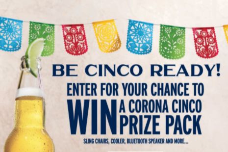 A refreshing beer sits in the foreground next to colorful papel picado decorations, inviting viewers to enter a contest for a festive prize pack, featured in the Corona Cinco Ready Sweepstakes
