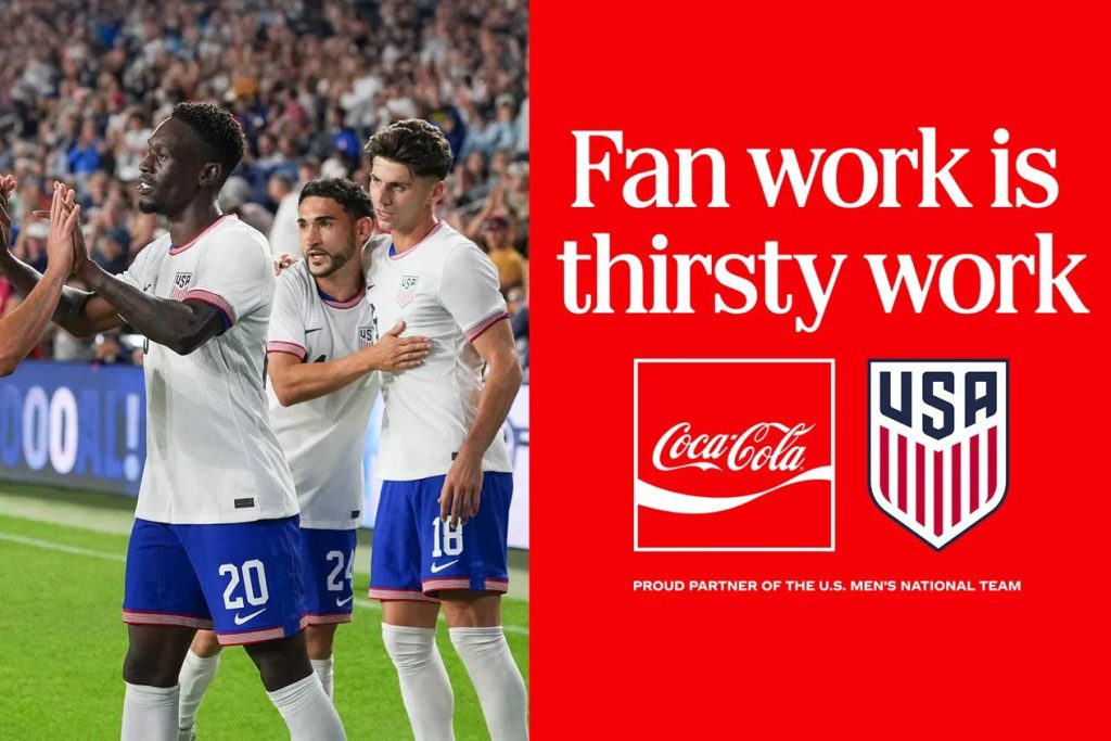 A group of soccer players in white jerseys celebrate on the field, with excitement and camaraderie visible as they high-five each other, surrounded by a lively crowd, featured in the Coca-Cola Match Day Getaway Sweepstakes