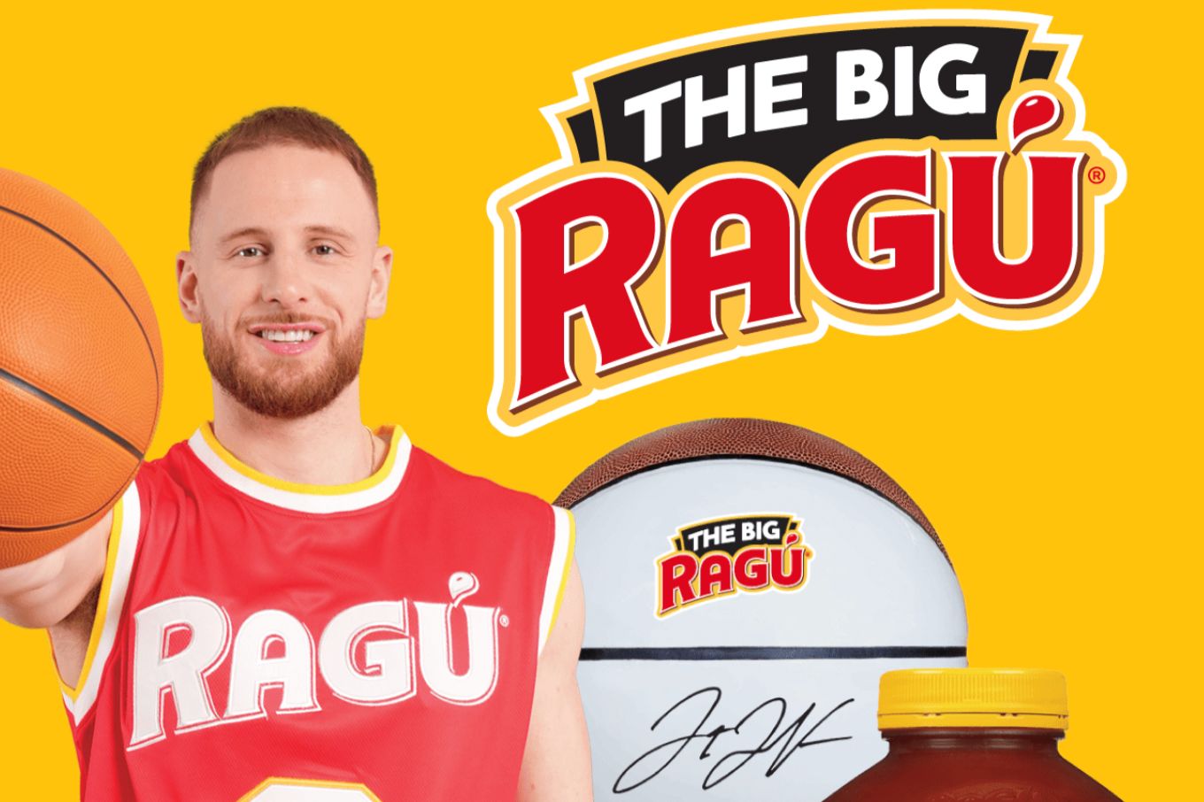 A smiling man in a red jersey holds a basketball while standing against a bright yellow background, accompanied by a basketball and jar of sauce, featured in the RAGÚ Basketball Kit Sweepstakes