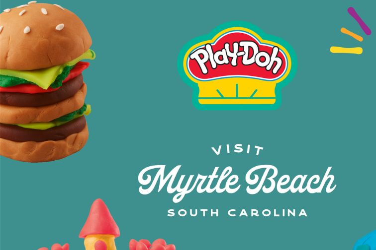 A fun, colorful Play-Doh burger stacked with layers of pretend ingredients, set against a bright teal background, inviting viewers to visit Myrtle Beach, South Carolina, featured in the Play-Doh Myrtle Beach Trip Sweepstakes