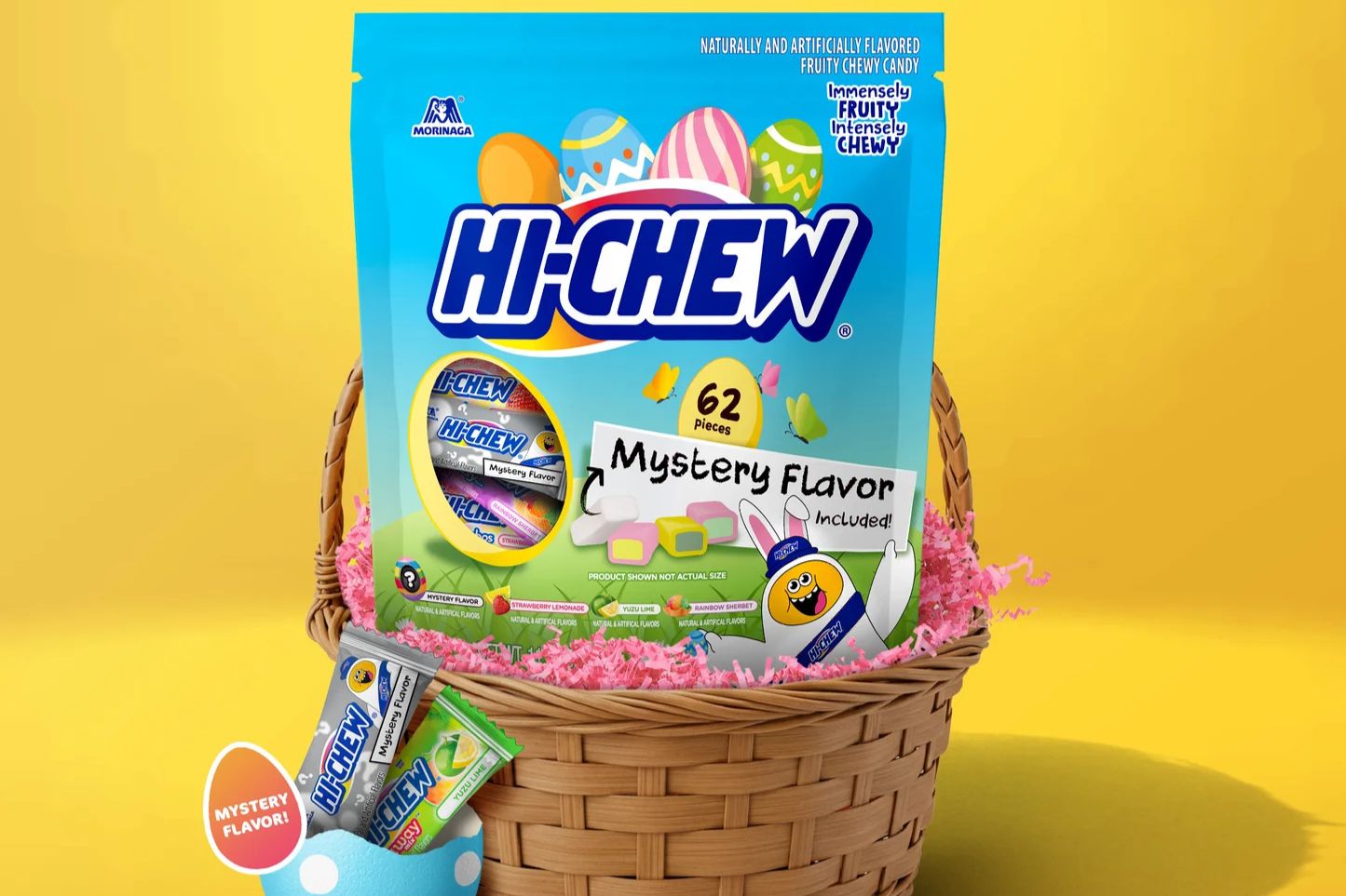 A colorful basket filled with pink grass contains a giant package of chewy candy along with smaller packets, set against a vibrant yellow background, featured in the HI-CHEW Easter Mystery Flavor Sweepstakes