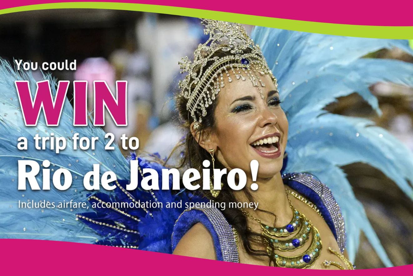 A joyful woman in a vibrant costume with feathers and a crown smiles brightly, capturing the excitement of a celebration while promoting a trip to Rio de Janeiro, featured in the Fernlea Flowers Relax in Rio Sweepstakes