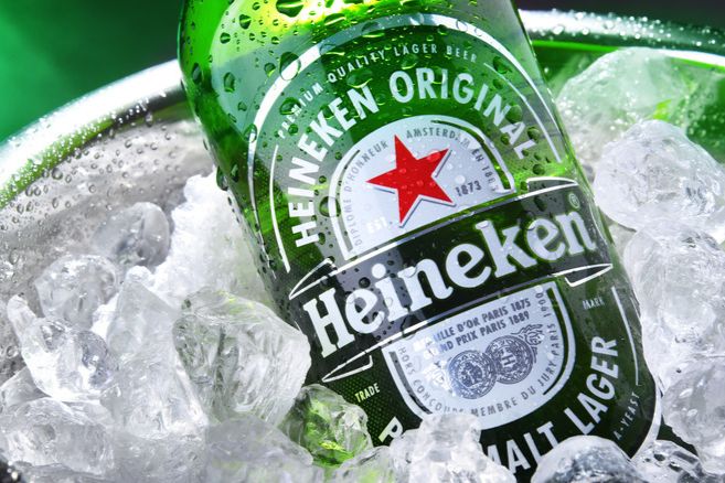 A chilled green bottle of lager surrounded by ice cubes glistens with condensation, showcasing a refreshing beverage ready to be enjoyed, featured in the Heineken Music Experience Sweepstakes