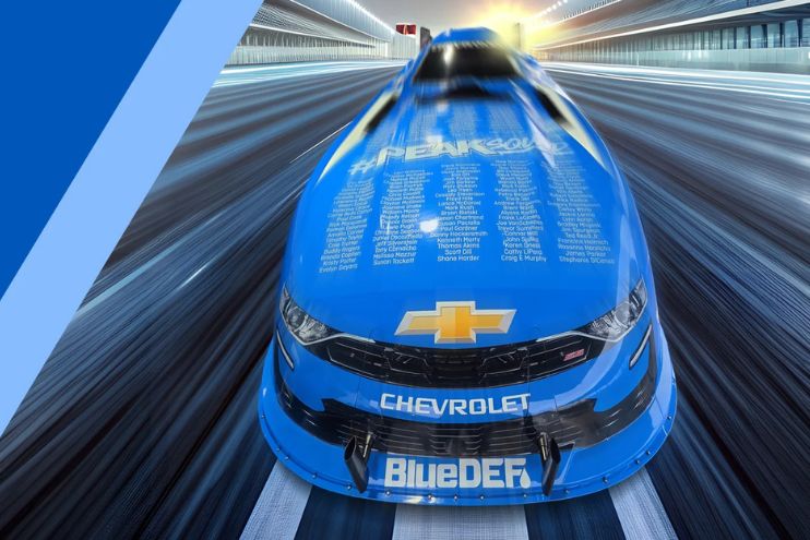 A sleek blue race car speeds down a blurred track, showcasing its aerodynamic design, ready for action in a high-speed motorsport event, featured in the PEAK John Force Hood Signing Sweepstakes