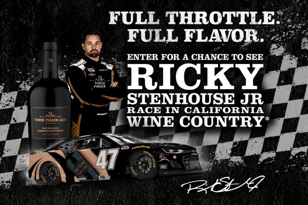A NASCAR driver stands confidently next to his race car, with a wine bottle in the foreground, promoting a chance to see him race in California's wine country, featured in the Three Finger Jack Ricky Stenhouse Jr. Sweepstakes