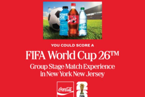 A soccer ball sits on grass next to three beverage bottles, promoting an exciting experience related to the FIFA World Cup in New York and New Jersey, featured in the Coca-Cola FIFA World Cup Sweepstakes