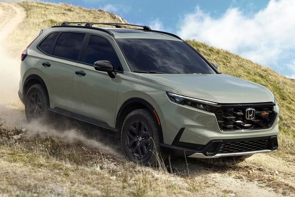 A sleek SUV navigates a rugged, dirt path with a hill in the background, kicking up dust as it moves confidently through the natural terrain. Bright blue skies peek through scattered clouds, featured in the Topgolf Honda CR-V Sweepstakes