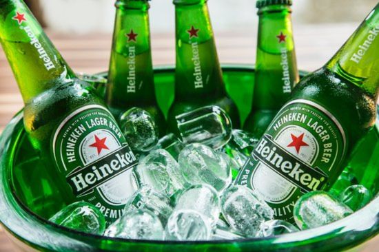 Chilled green bottles of beer rest amid ice cubes in a clear bowl, showcasing a refreshing beverage scene perfect for a gathering or celebration, featured in the Heineken Nashville SC Sweepstakes