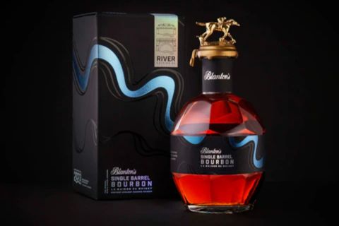 A stylish bottle of bourbon with a unique horse-shaped stopper sits next to an elegantly designed box featuring flowing blue graphics. The rich amber liquid contrasts with the dark background, featured in the Double Neat Blantons Sweepstakes