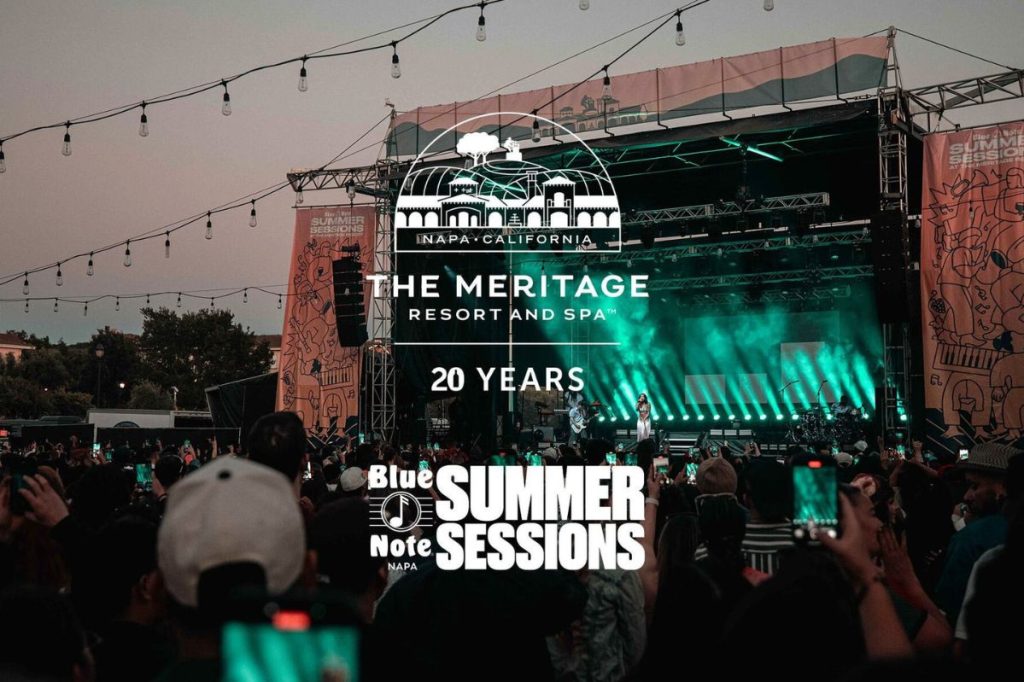 A lively outdoor concert scene with a large crowd, illuminated by green stage lights, as a performer sings energetically on stage, creating a festive atmosphere, featured in the Meritage Resort Two-Night Sweepstakes