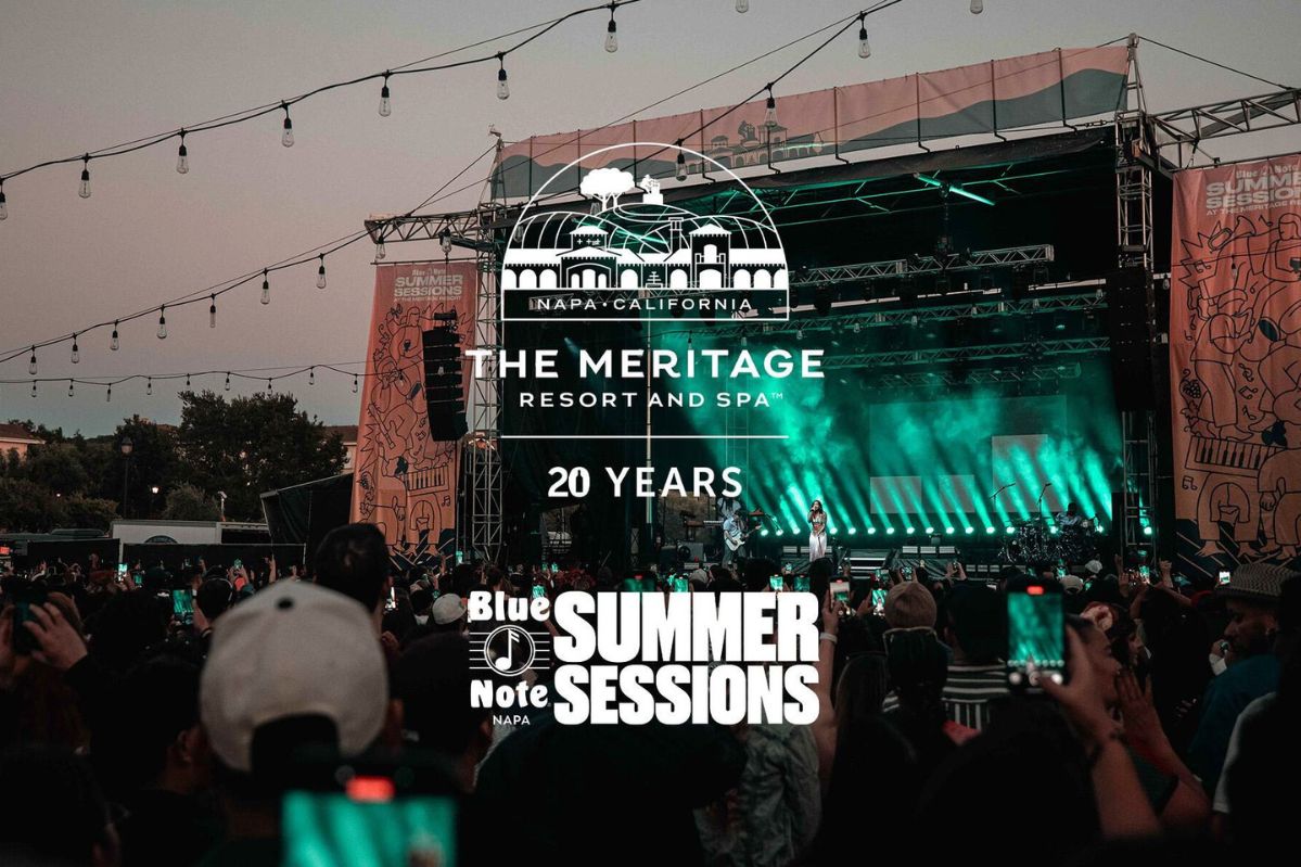 A lively outdoor concert scene with a large crowd, illuminated by green stage lights, as a performer sings energetically on stage, creating a festive atmosphere, featured in the Meritage Resort Two-Night Sweepstakes