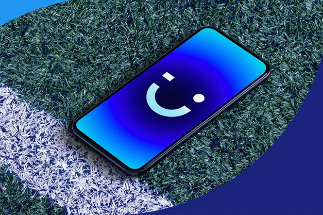 A smartphone displaying a smiling face icon rests on a patch of green grass next to a white line, suggesting a connection to sports or outdoor activities, featured in the 2026 Visible by Verizon x FIFA Sweepstakes