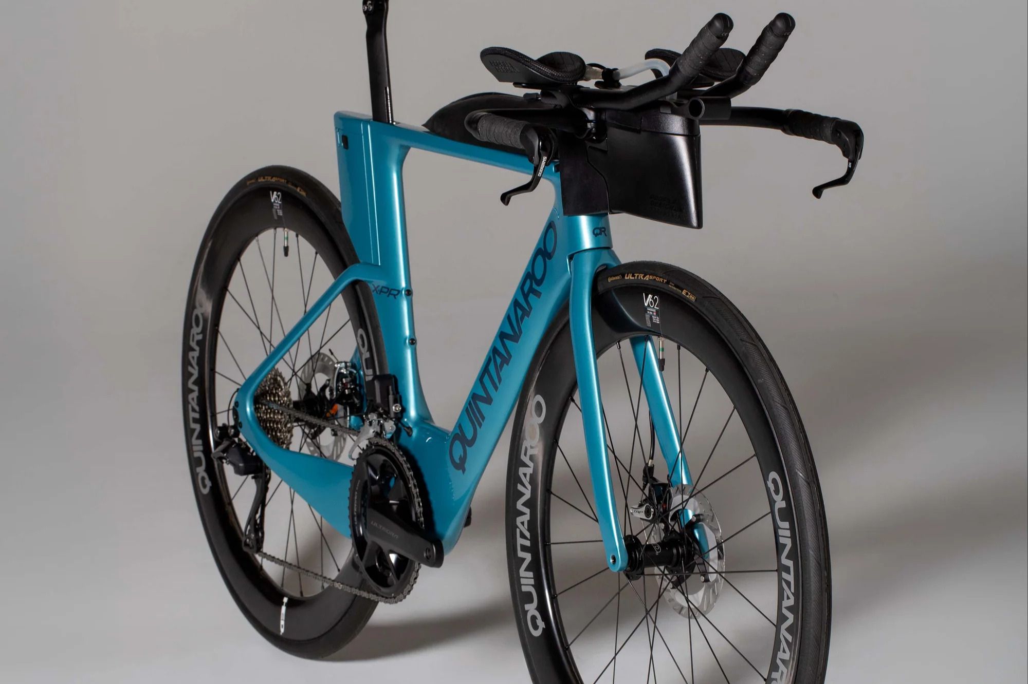 A sleek blue triathlon bike is positioned at an angle, showcasing its aerodynamic frame, drop handlebars, and disc brakes against a neutral background, featured in the American Bicycle Group Frameset Sweepstakes