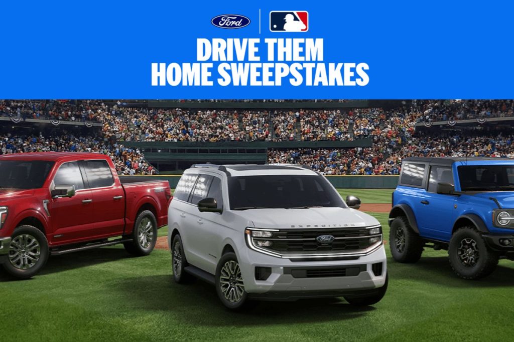 A baseball stadium filled with fans features three vehicles on the grass: a red truck, a white SUV, and a blue off-road vehicle, showcasing their sporty designs and spaciousness, featured in the Ford Drive Them Home Sweepstakes