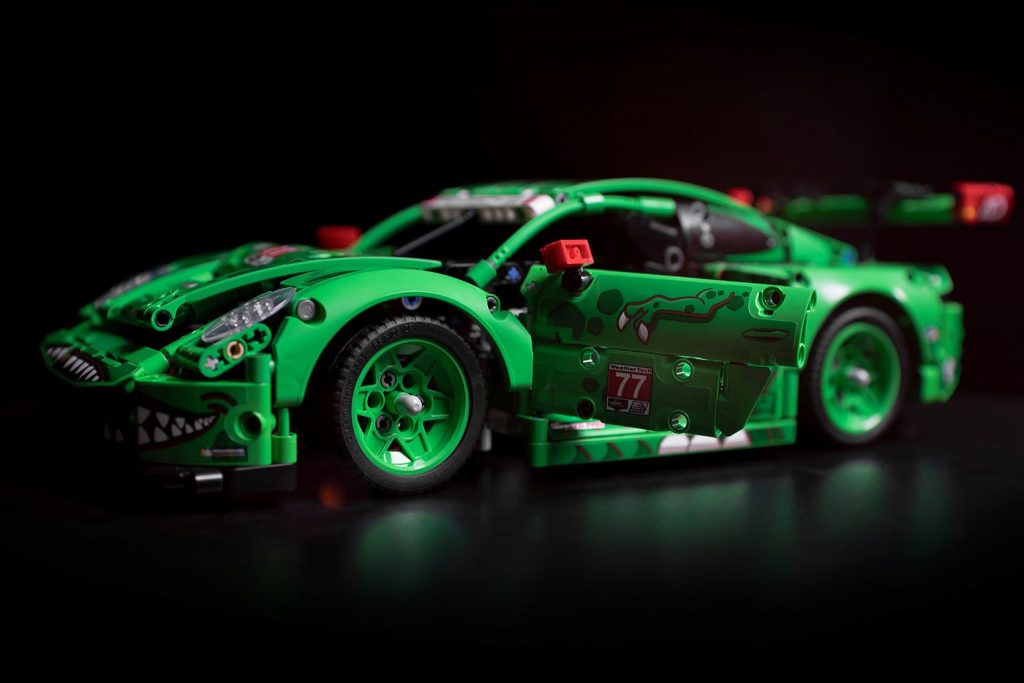 A vibrant green toy race car with intricate designs is showcased on a dark surface, highlighting its sleek body, detailed wheels, and open doors, emphasizing its dynamic racing aesthetic, featured in the Mobil 1 LEGO Porsche Sweepstakes