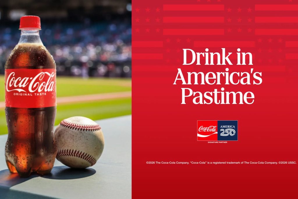 A chilled bottle of soda stands next to a baseball on a table, with a lively baseball field blurred in the background, representing America's favorite pastime, featured in the Coca-Cola America 250 Baseball Sweepstakes