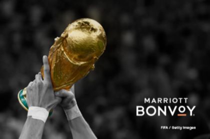 A pair of hands lifts a gold trophy against a blurred crowd, celebrating victory in a renowned sports event, featured in the Visa Sleepover Suite Sweepstakes