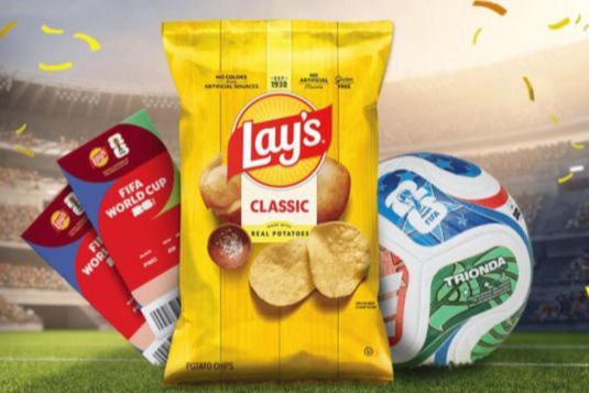 A vibrant scene features a bag of Lay's Classic chips alongside FIFA World Cup tickets and colorful soccer balls, set against a stadium backdrop, featured in the Lays FIFA World Cup Tickets Sweepstakes
