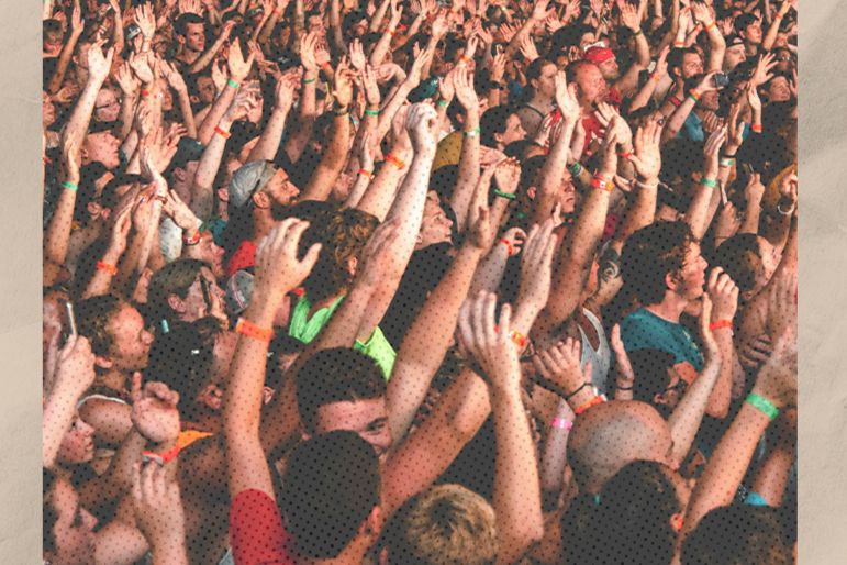 A vibrant crowd of enthusiastic concertgoers raises their hands in excitement, immersed in the live music atmosphere, showcasing a diverse and engaged audience, featured in the Morton Salt Movers & Shakers Sweepstakes