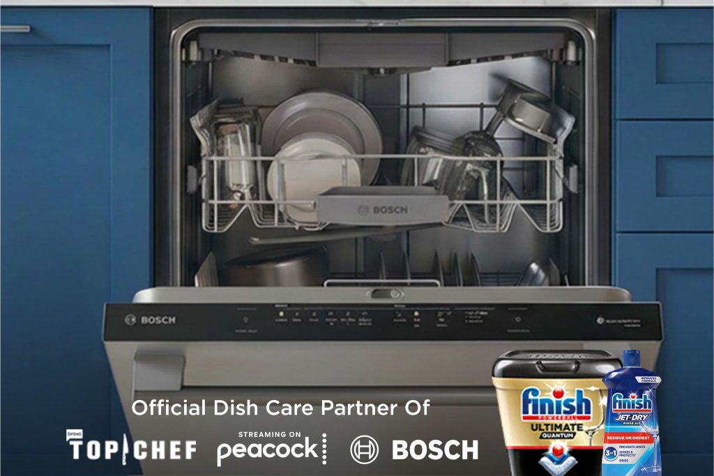 A Bosch dishwasher is fully loaded with clean dishes, including plates, glasses, and pots, showcasing its interior design against a blue kitchen backdrop, featured in the Finish Top Chef x Bosch Sweepstakes