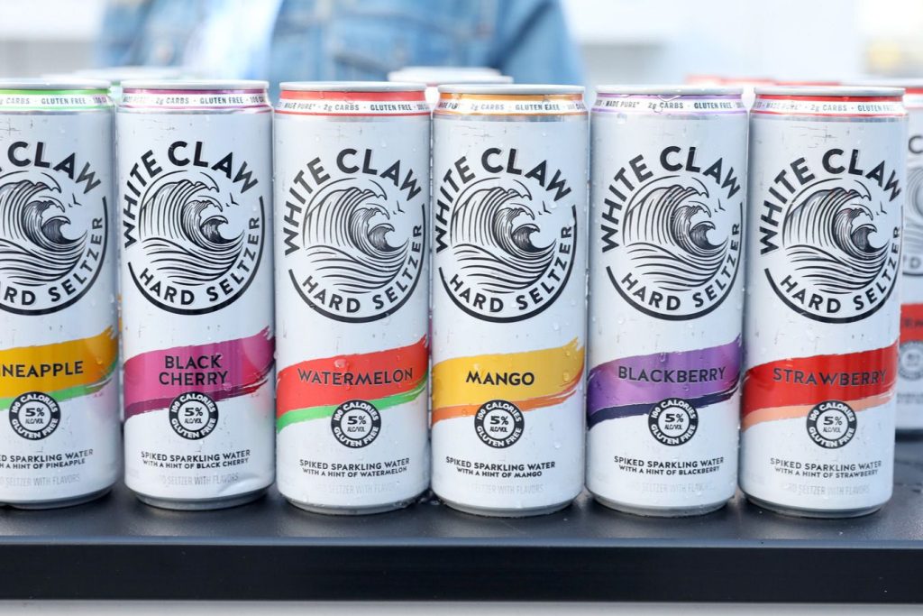 A selection of colorful hard seltzer cans arranged neatly on a surface, showcasing various flavors like pineapple, black cherry, watermelon, mango, blackberry, and strawberry, featured in the White Claw Music Festival Tickets Sweepstakes