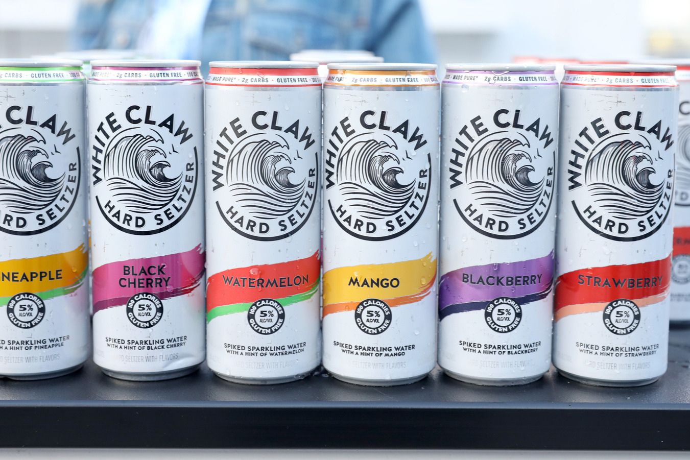 A selection of colorful hard seltzer cans arranged neatly on a surface, showcasing various flavors like pineapple, black cherry, watermelon, mango, blackberry, and strawberry, featured in the White Claw Music Festival Tickets Sweepstakes