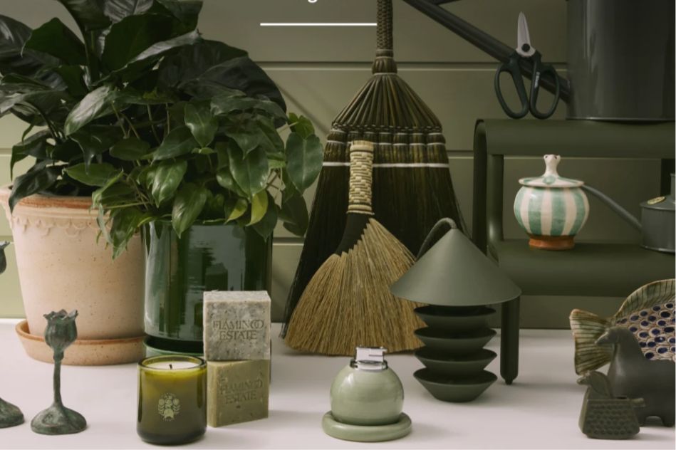 A collection of home and garden decor items, including potted plants, a broom, a variety of decorative objects, and candles arranged on a table in a cozy setting, featured in the Goodee Gardening Favorites Sweepstakes