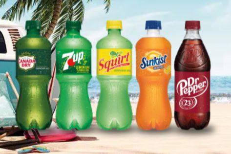 A beach scene features five colorful bottles of soda arranged in line, showcasing different flavors against a backdrop of sand and palm trees, featured in the No Bummer Summer 2026 Sweepstakes
