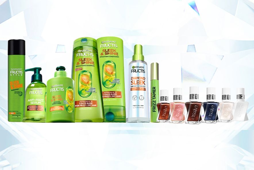 A colorful assortment of hair and nail care products is displayed, featuring various shampoos, conditioners, and nail polishes arranged against a light backdrop, featured in the Diamond Like Shine Sweepstakes