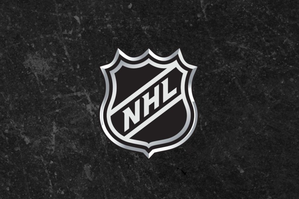 A silver NHL shield logo stands out against a textured black background, highlighting the iconic shape and lettering associated with professional ice hockey, featured in the NHL Stanley Cup Playoffs Sweepstakes