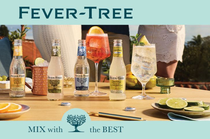 A sunny outdoor scene features a table set with various drinks, including colorful cocktails and bottles of tonic water, surrounded by fresh lime and orange slices, featured in the Fever-Tree $5,000 Sweepstakes