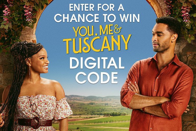 A cheerful woman in a floral dress smiles at a man in a rust-colored shirt, both standing in an archway with a scenic view of rolling hills in the background, featured in the You, My & Tuscany Instant Win