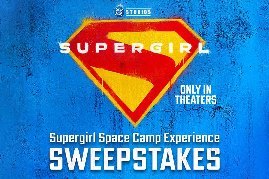 A bright blue background features the iconic Supergirl emblem, accompanied by text promoting the Supergirl Space Camp Experience sweepstakes, emphasizing "Only in Theaters.", featured in the Cold Stone Creamery Supergirl Space Camp Sweepstakes